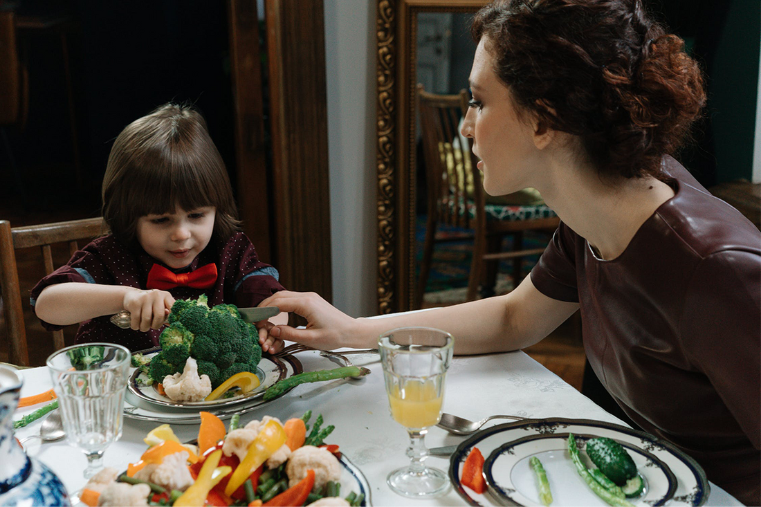 A mom getting her kid to eat vegetables 